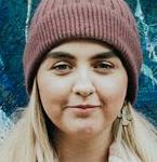 Woman posing in front of angel wings street art in Bangor, Wales.